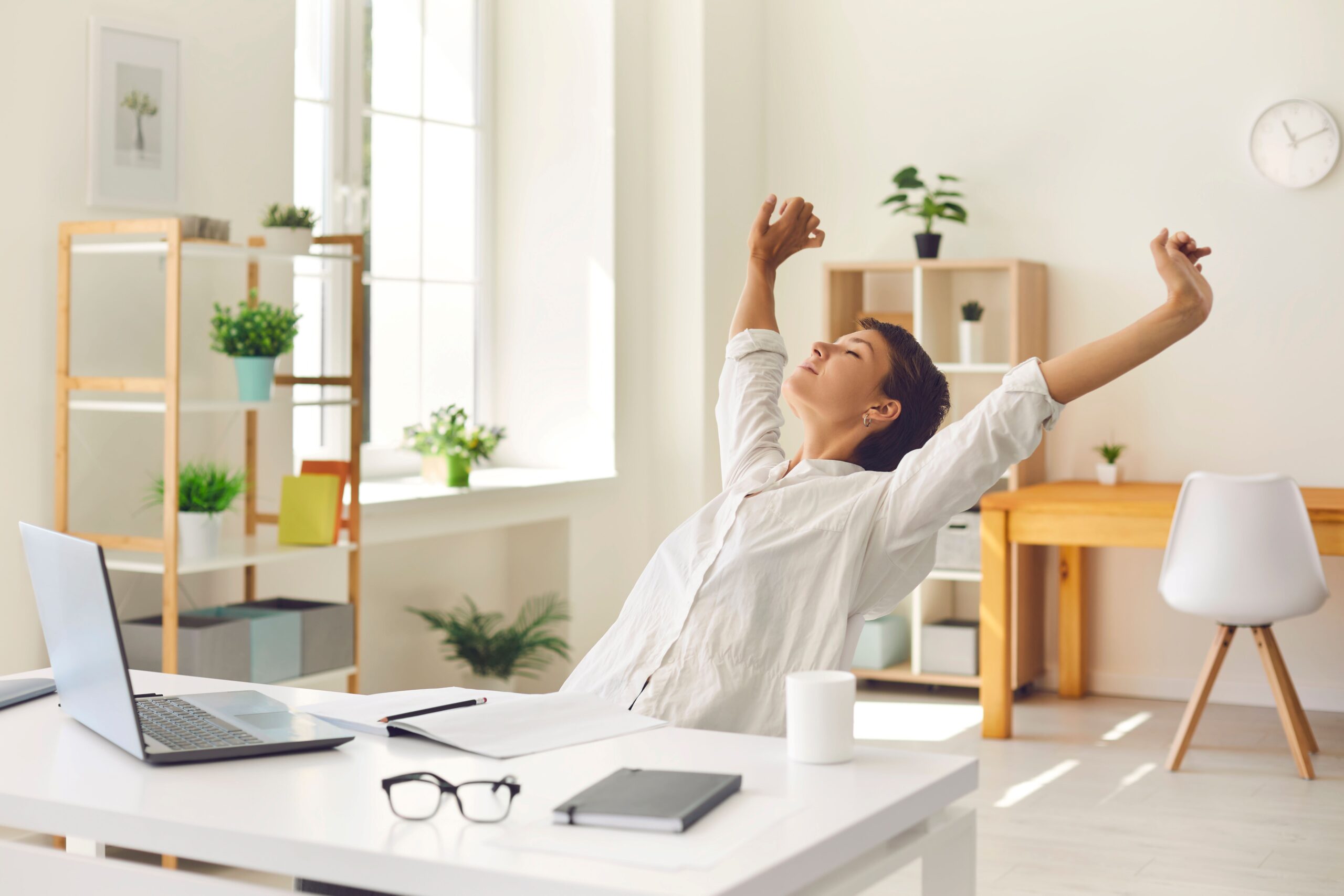 Eine Frau macht eine Pause am Arbeitsplatz und streckt sich